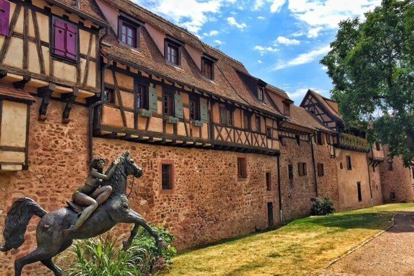 A traditional half-timbered building with a horse statue in the foreground. 1