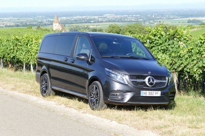 A black Mercedes van parked on a rural road with vineyards and a distant church in the background. 5