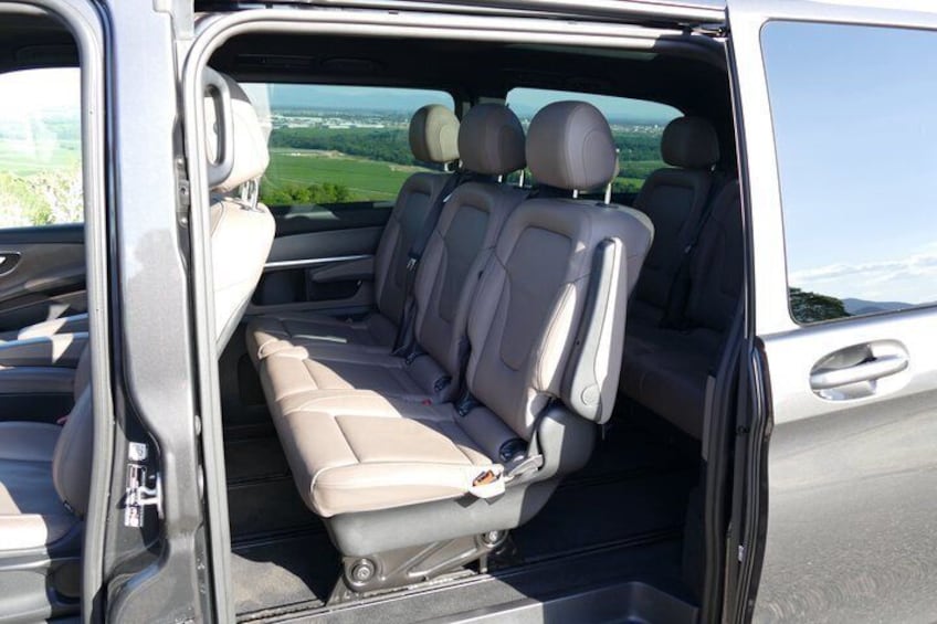 A vehicle interior with a bench seat, headrests, and a rearview mirror. 4