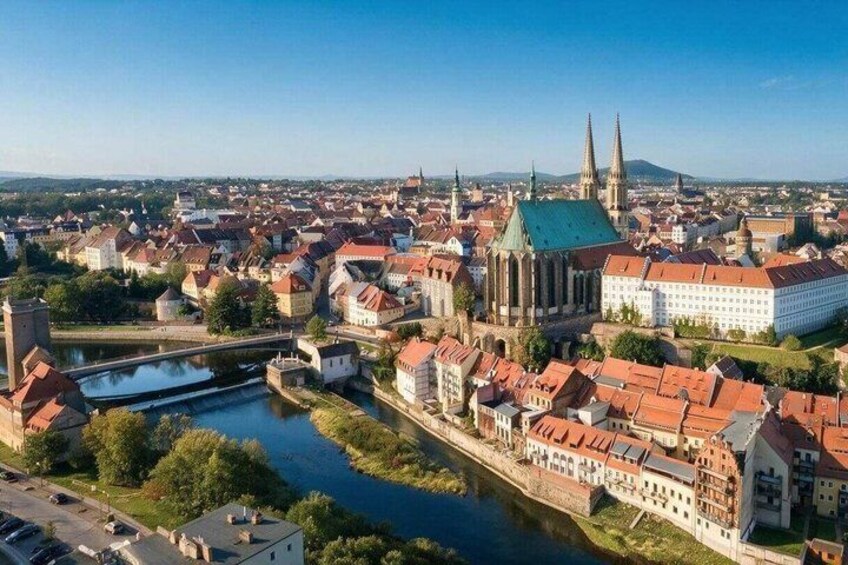 A cityscape with a prominent church, a river, and a hill in the background. 1