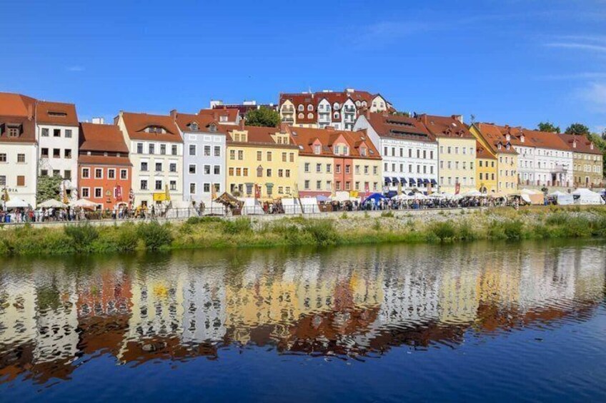 A river with buildings reflecting on the water, a clear sky, and a bridge in the background. 2