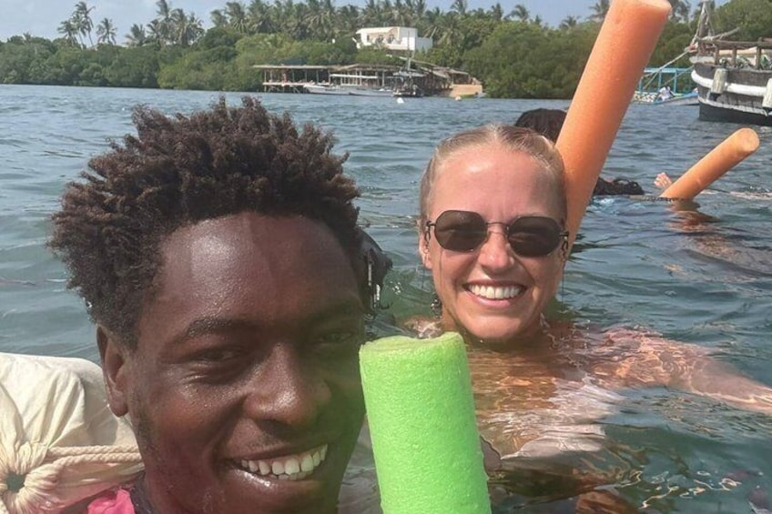 Two people in a body of water with a green object and a boat in the background. 5