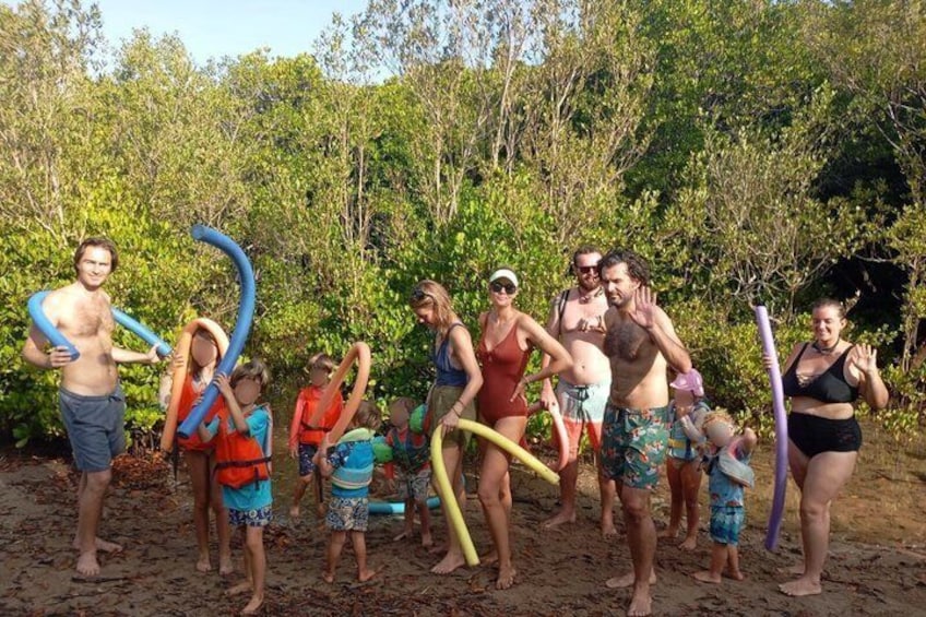A group of people on a sandy beach with trees in the background. 1