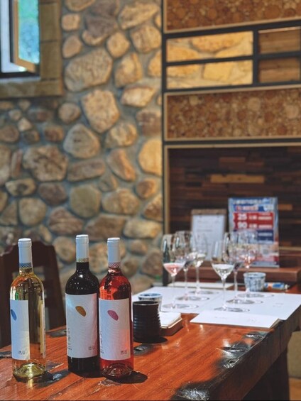 A wooden table with three wine bottles and several glasses. 4
