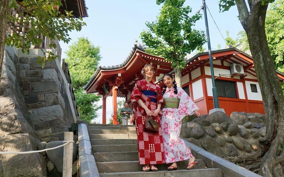 A traditional Japanese building with a red and white color scheme, stone steps, and a tree in the foreground. 2