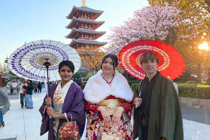 Three people holding umbrellas, a traditional pagoda, and cherry blossoms. 1