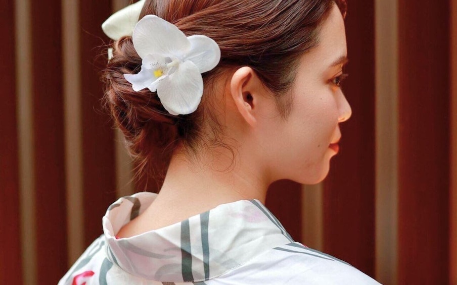 A person with a white flower in their hair, wearing a garment with a striped pattern. 5