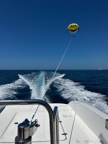 A parasail with a yellow and white design, a wake in the water, and a distant boat on the horizon. 4