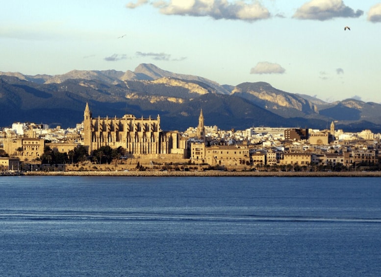 A coastal city with a prominent cathedral and mountains in the background. 1