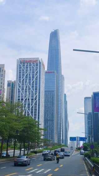 A city street lined with modern skyscrapers, vehicles on the road, and clear skies. 4