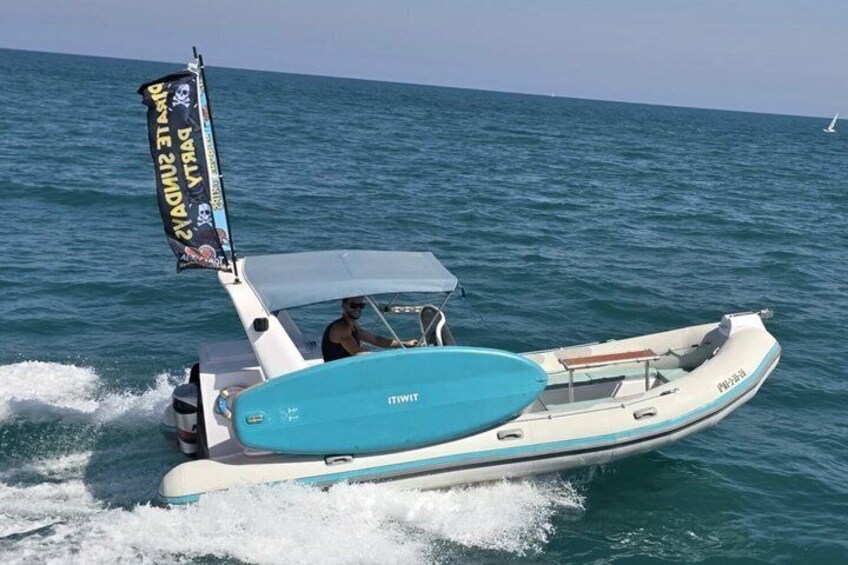 A speedboat with a blue and white color scheme, a person at the helm, and a banner on the mast. 5