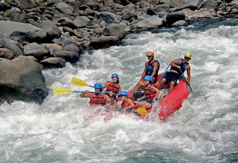 A group of people rafting on a river with rapids, surrounded by rocks. 3