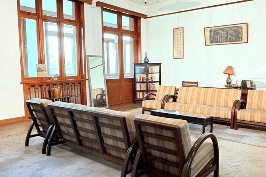 A traditional living room with wooden furniture, large windows, and a bookshelf. 5