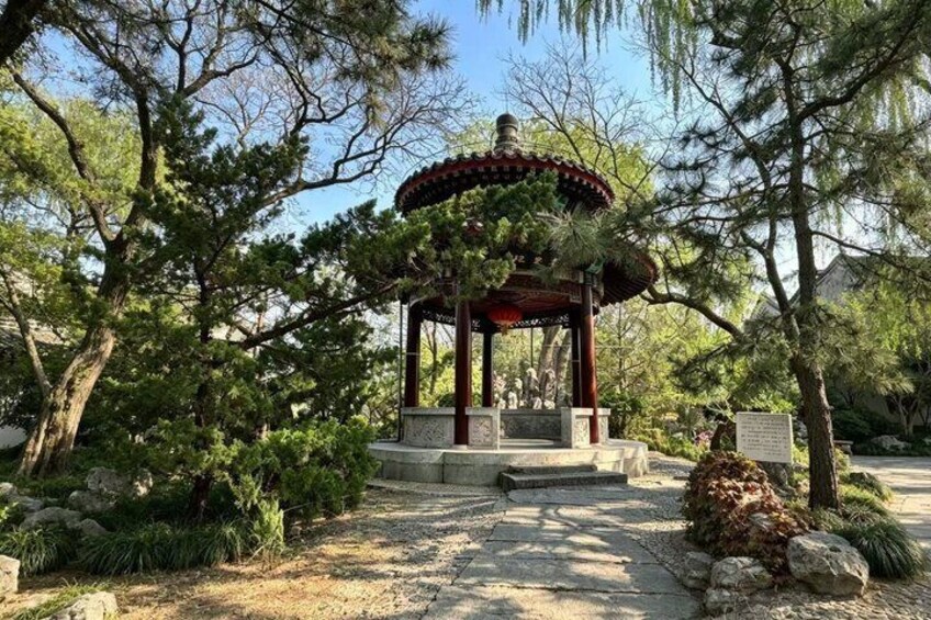 A traditional gazebo surrounded by trees and rocks. 2