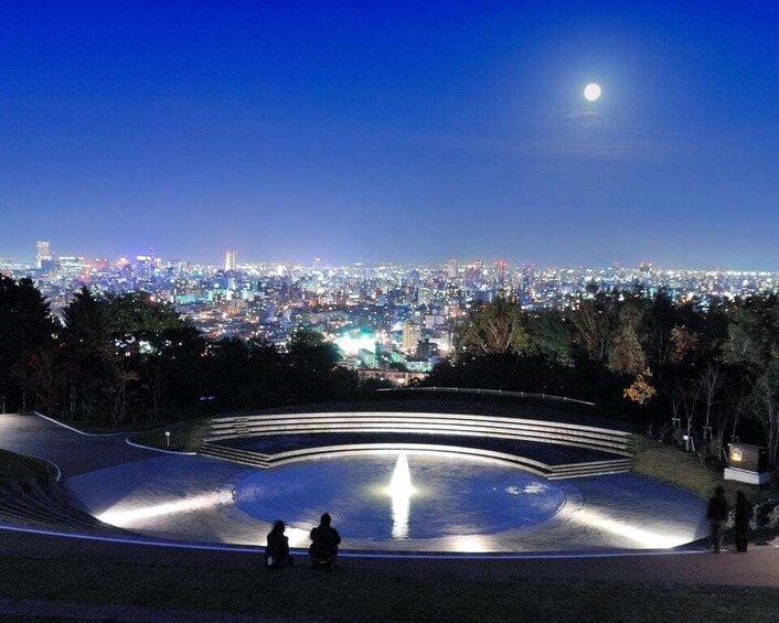 A nighttime cityscape with a park featuring a circular amphitheater. 4