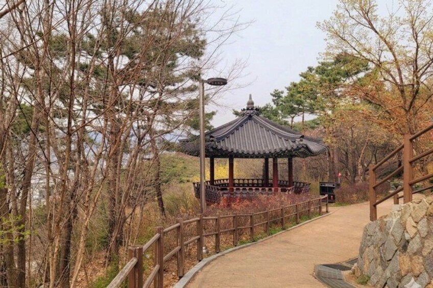 A traditional pavilion, a stone pathway, and a wooden fence in a park. 3