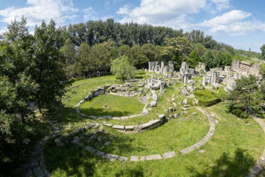 Ancient ruins with stone pathways and structures surrounded by greenery. 3