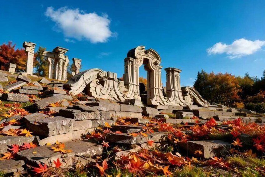 Ancient ruins with columns and arches, surrounded by autumn leaves. 2