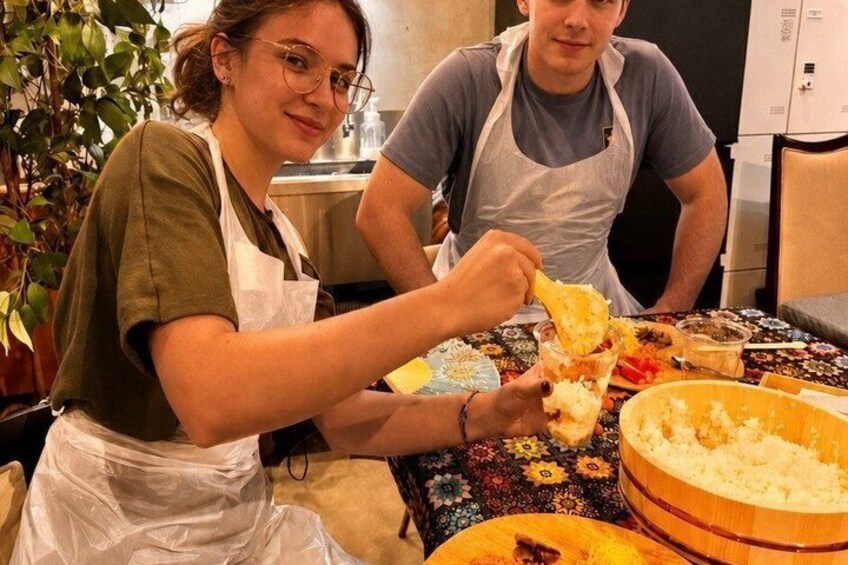 Two people wearing aprons, one cutting food and the other holding a piece of food. 5