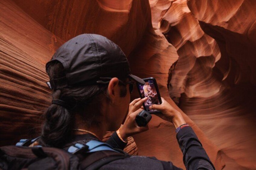A person taking a photo in a narrow canyon with red rock walls. 1