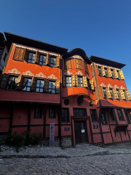A red building with ornate window frames and a stone facade. 5