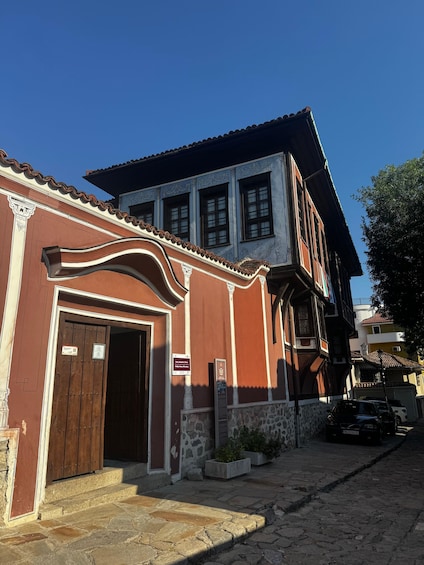 A traditional building with a red facade, a wooden door, and a stone base. 3