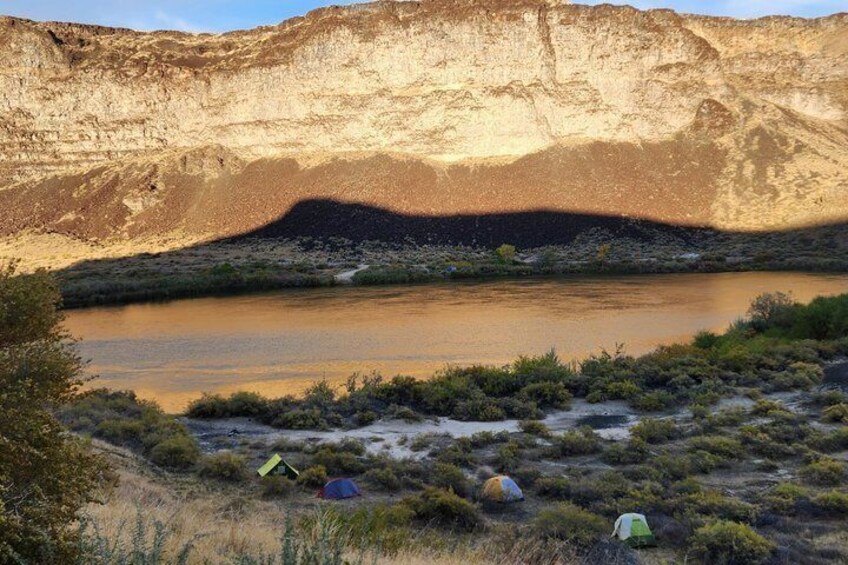 A river, tents, and a cliff. 4
