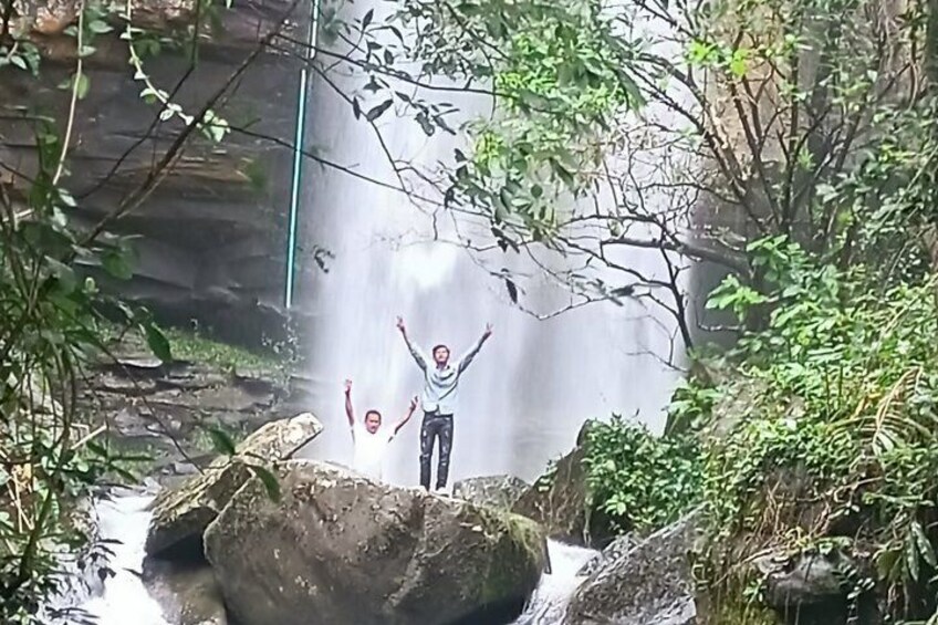 A waterfall with rocks and greenery. 1