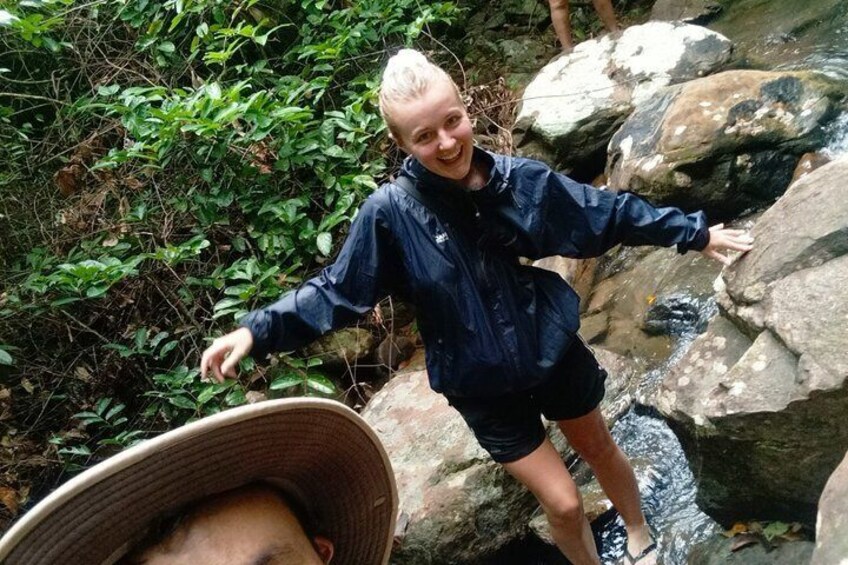 A person standing on rocks near a stream in a forested area. 5