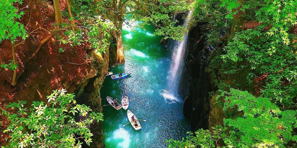 A river with boats, surrounded by dense green foliage and a waterfall. 1
