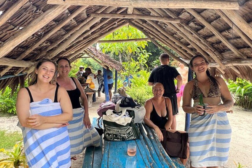 A group of people under a wooden shelter with a blue table in the center. 3