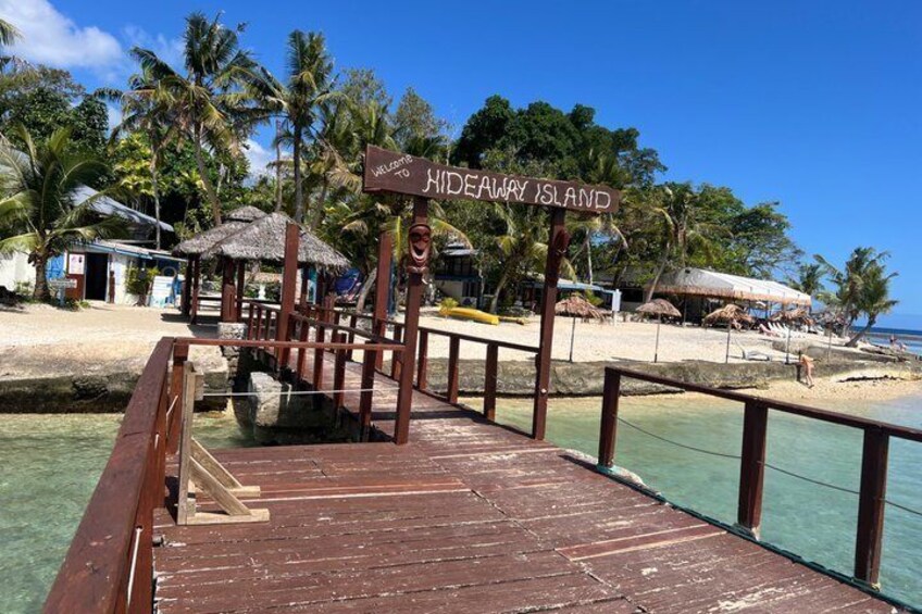 A wooden pier leading to a beach with a sign reading 'Hideaway Island.' 3