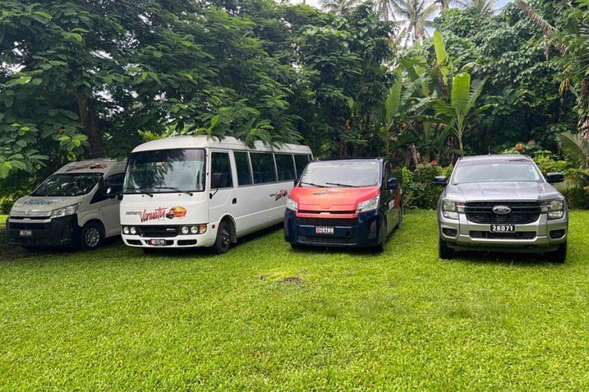 Four vehicles parked on a grassy area with dense foliage in the background. 5