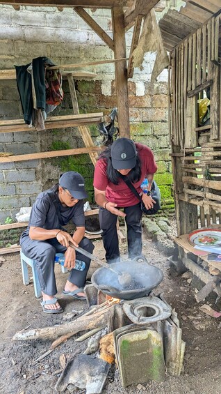 Two people cooking outdoors with a traditional stove and pots. 2