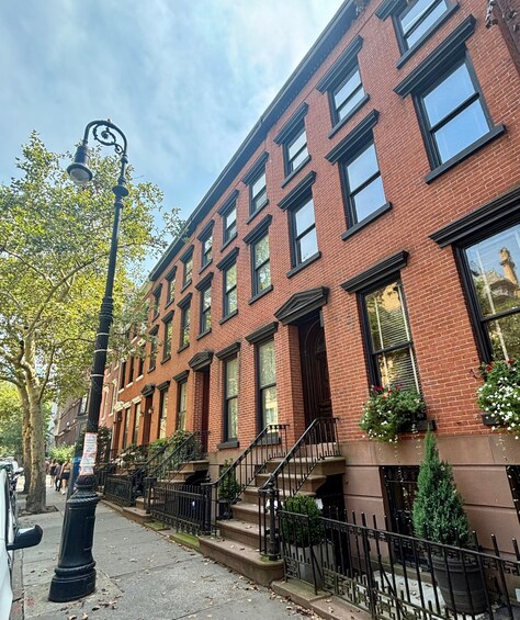 A row of red brick buildings with black window frames and a street lamp. 5