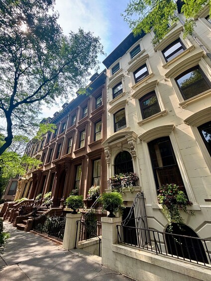 A row of brownstone row houses with white trim and black railings. 2