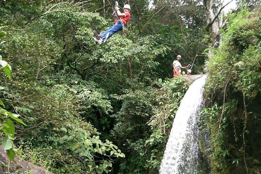 A person zip-lining through a forested area with a waterfall. 4