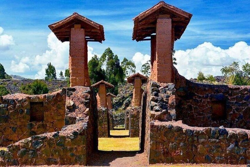 Ancient stone structures with wooden roofs, a pathway, and a mountainous landscape. 4