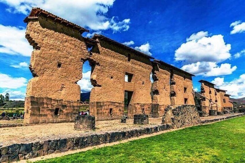 Ancient ruins with stone walls and arches, a grassy field, and a clear blue sky. 2