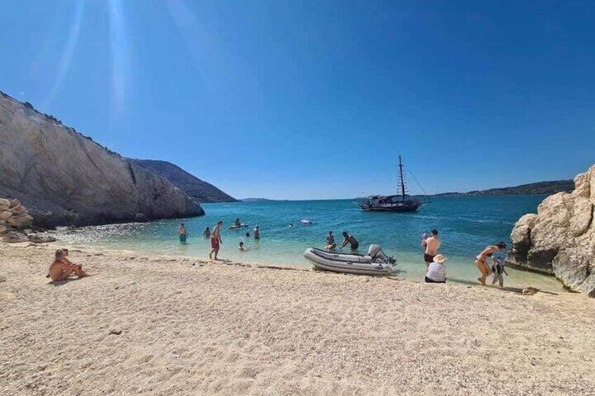 A beach with people, a boat, and a sailboat in the water. 3