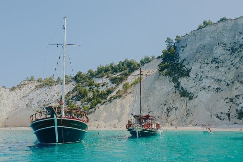 Two boats on turquoise water with a rocky cliff in the background. 1