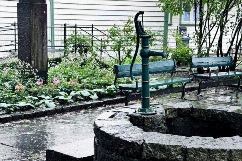A stone well, a green bench, and a fence in a garden. 4