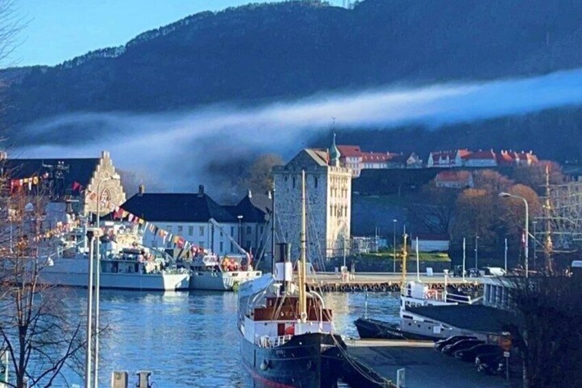 A harbor with boats, a prominent tower, and buildings in the background. 1