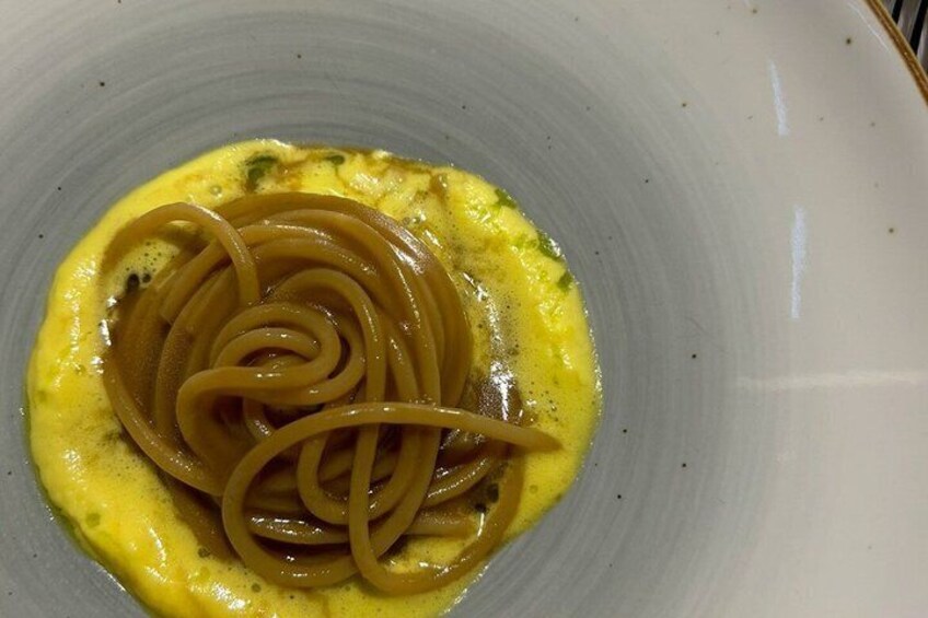 A plate of spaghetti with a yellow sauce. 2