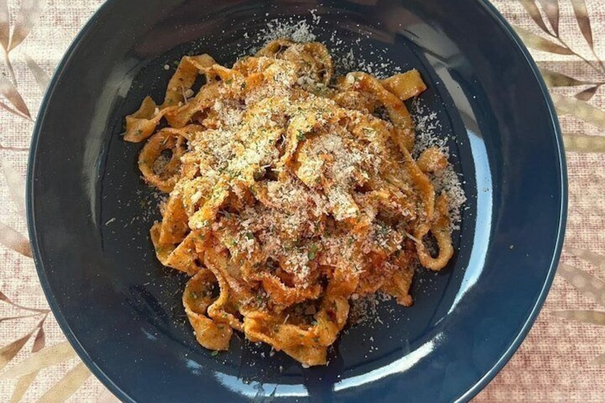 A plate of pasta with a tomato-based sauce and grated cheese. 3