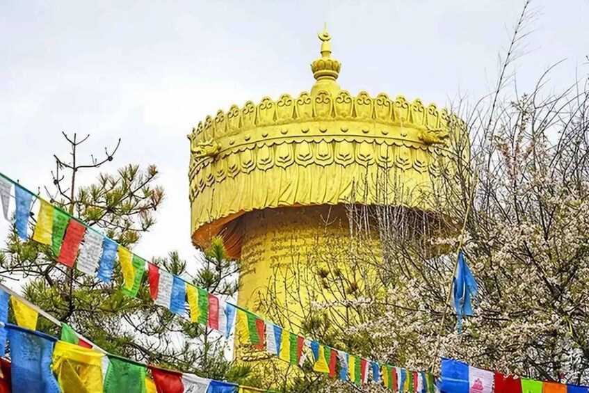 A golden structure with a dome, surrounded by trees and colorful prayer flags. 2
