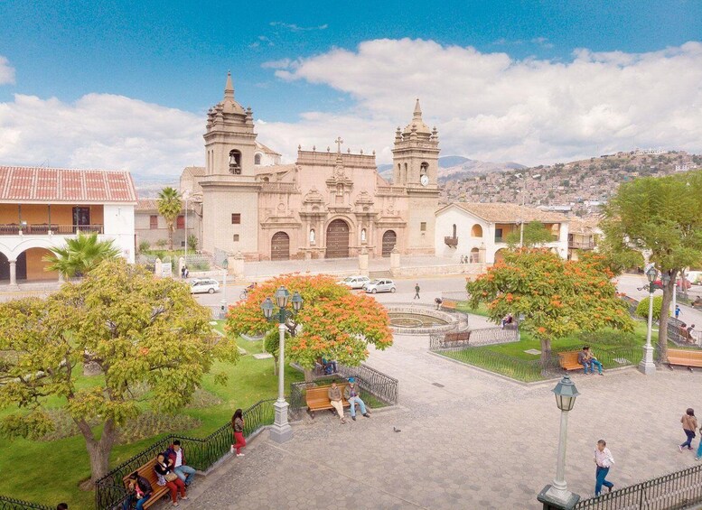 A historic church with two bell towers, surrounded by a park with benches and trees. 2