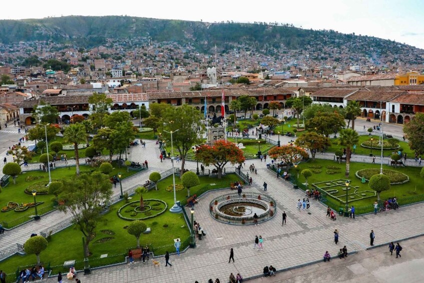 A city square with trees, a fountain, and buildings in the background. 1