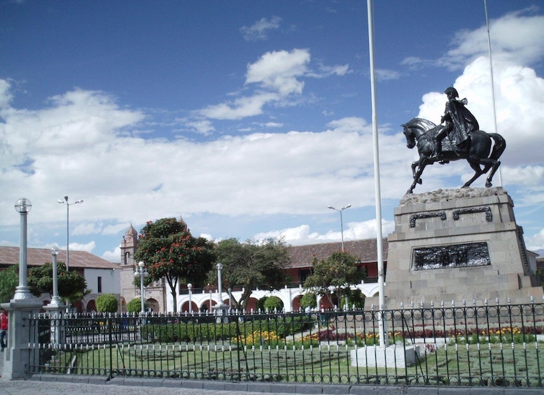 A statue of a man on horseback, a fountain, and a building with arches in the background. 3