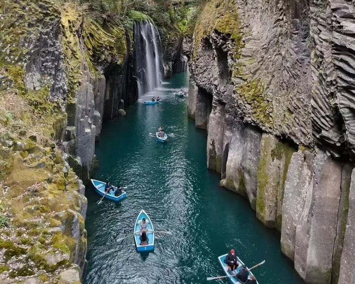 A narrow canyon with a waterfall and people paddling kayaks. 5